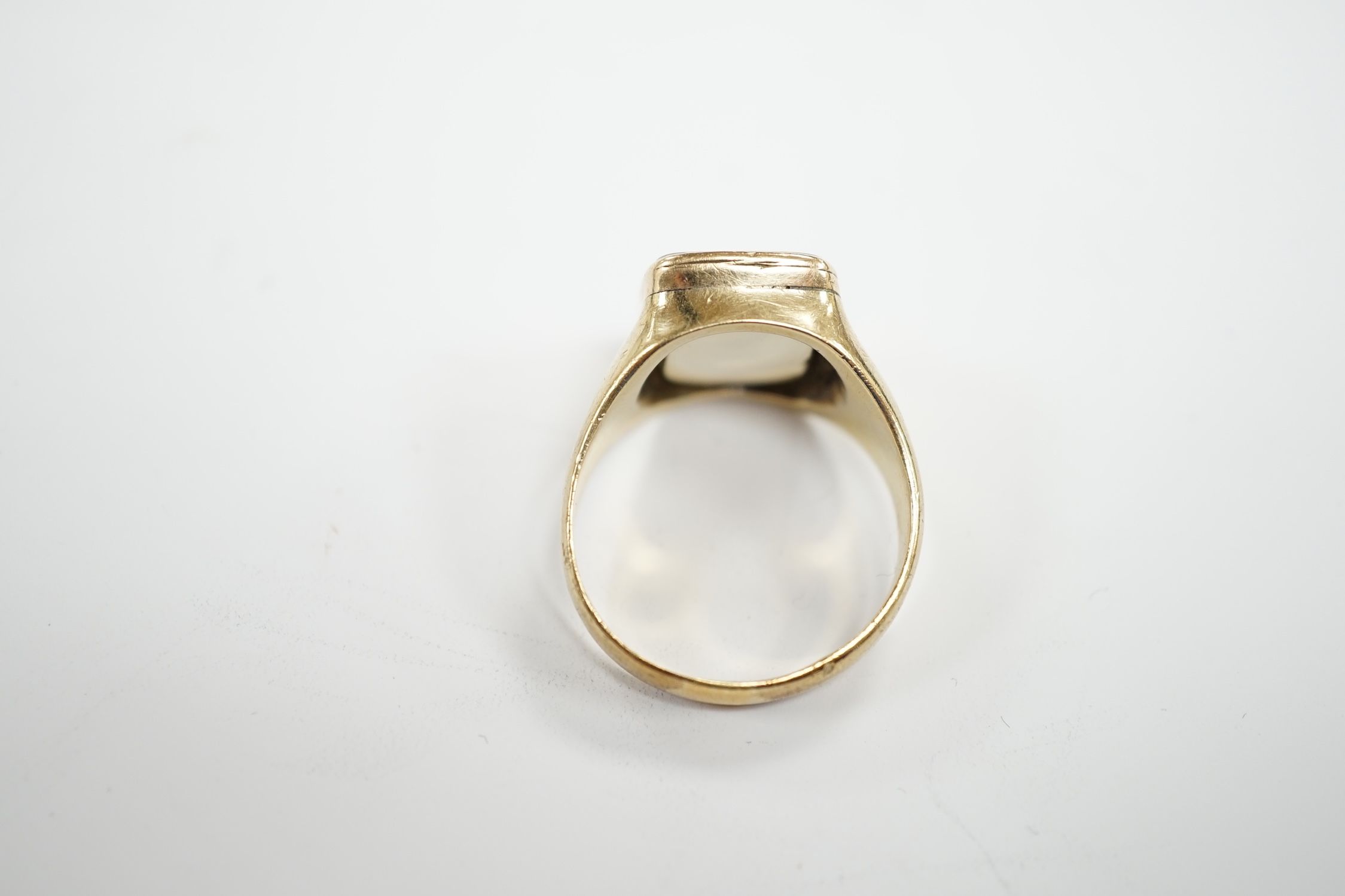 An early 20th century yellow metal and white chalcedony intaglio ring, the matrix carved with the motto 'Virtutum Extendere Factis' with crest, size W, gross weight 9.4 grams.